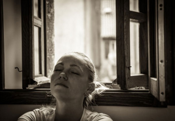 Грустная девушка с закрытыми глазами сидит у окна