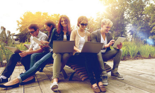 Студенты сидят на улице. Каждый зависает в ноутбуке или телефоне