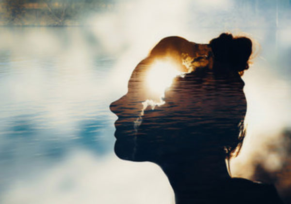 Лицо женщины в тени. Внутри головы светит солнце. На заднем плане небо