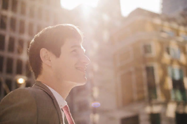 Улыбающийся мужчина идет по улице. Светит солнце