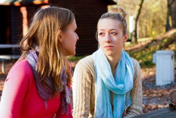 Две девушки сидят на улице. У одной очень грустное лицо