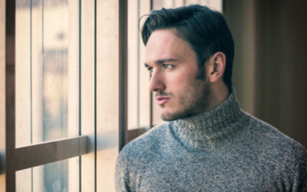 Серьезный симпатичный мужчина стоит у окна