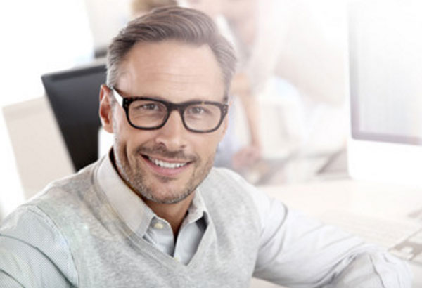 Мужчина в очках на работе. Он улыбается