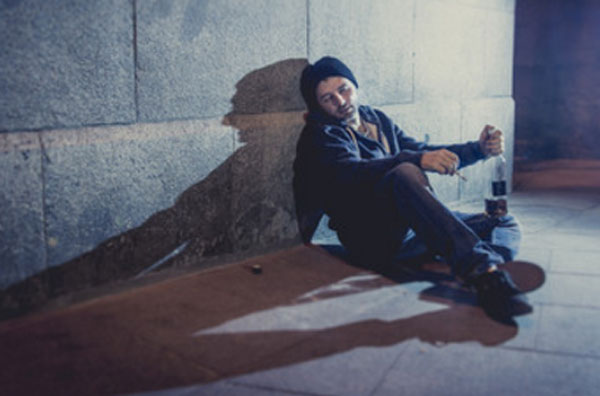 Мужчина с бутылкой в руках валяется на улице