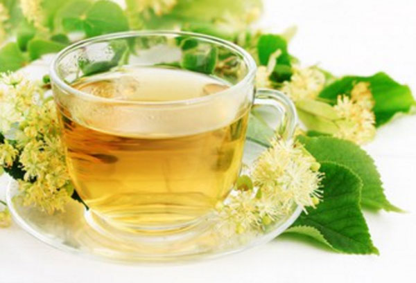 Чашка липового чая. Рядом лежат соцветия липы