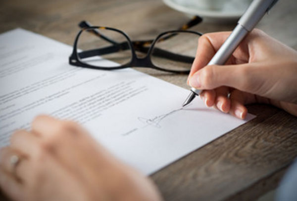 Человек ставит подпись на листке бумаги