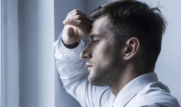 Мужчина стоит у окна, куда-то печально глядит