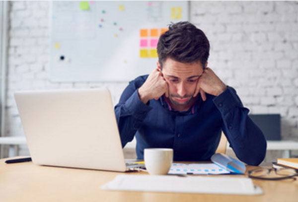 Угрюмый мужчина сидит за рабочим столом