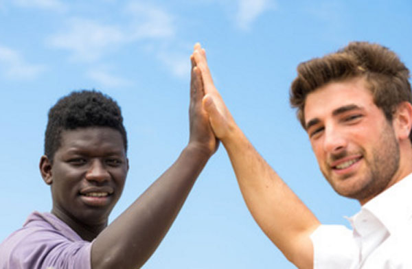 Мужчина европеоидной расы прижимает ладонь к ладони мужчины негроидной расы