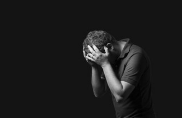 Мужчина в темноте хватается за голову