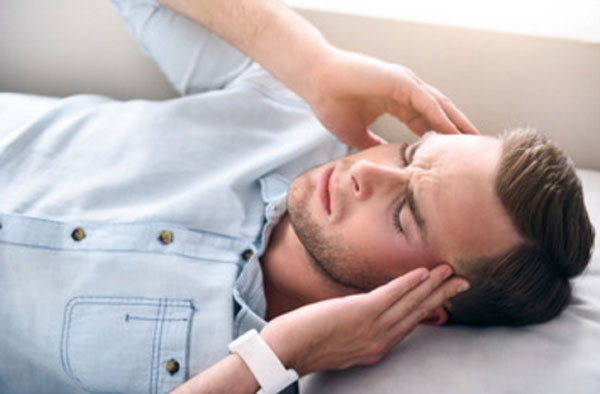 Мужчина лежит и держится за виски