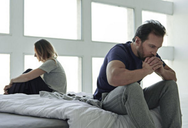 Немолодые мужчина и женщина сидят по разные стороны кровати в задумчивости. У них проблемы в отношениях