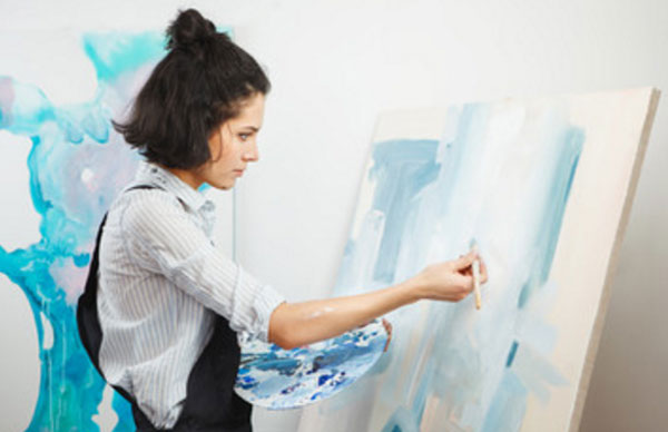 Девушка рисует на мольберте