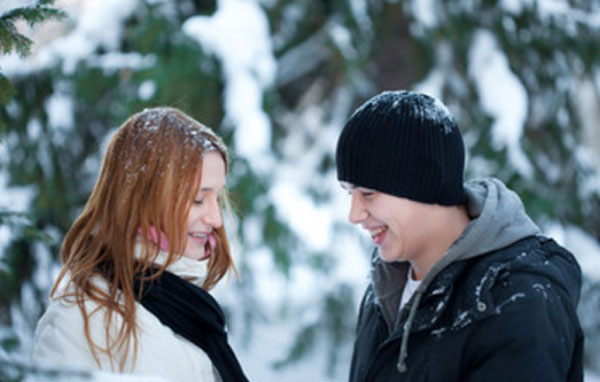 Девушка с парнем стоят друг напротив друга в зимнем парке