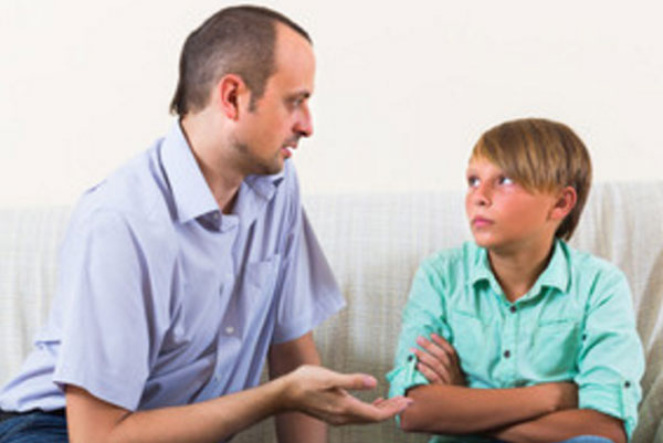 Отец что-то объясняет расстроенному мальчику