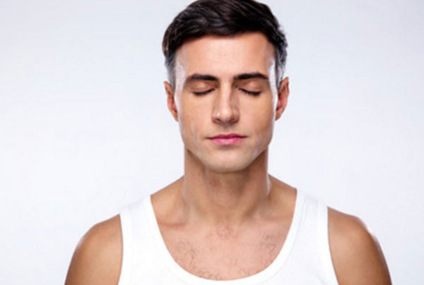 Скрытный мужчина стоит в майке с закрытыми глазами