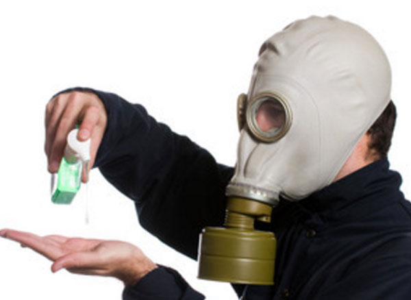 Мужчина в противогазе капает на руку дезинфицирующее средство