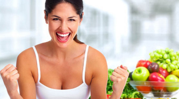 Женщина радуется. Рядом с ней миска с фруктами