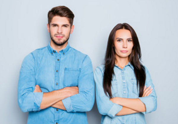 Серьезные мужчина и женщина стоят со скрещенными руками