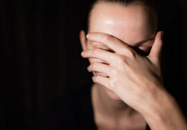 Женщина прикрывает лицо рукой