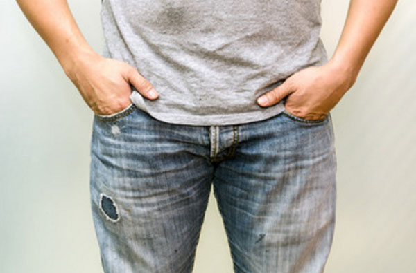 Мужчина с руками, спрятанными в карманы джинс. Большие пальцы высунуты наружу