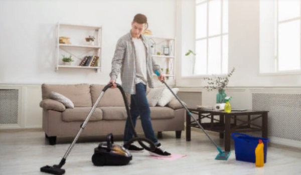 Мужчина пылесосит комнату