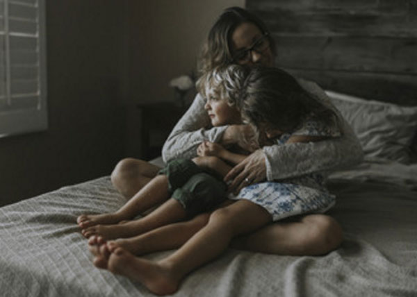 Женщина обнимает своих детей