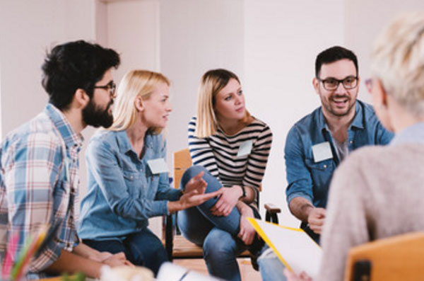 Дискуссия молодых людей, которые сидят на стульях. Рядом сидит психолог