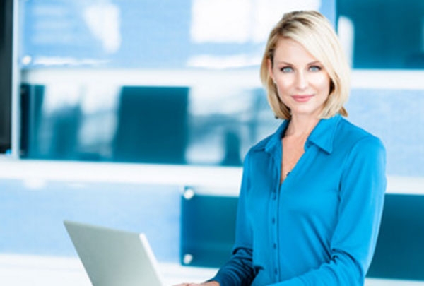 Женщина в светло синей рубашке за ноутбуком