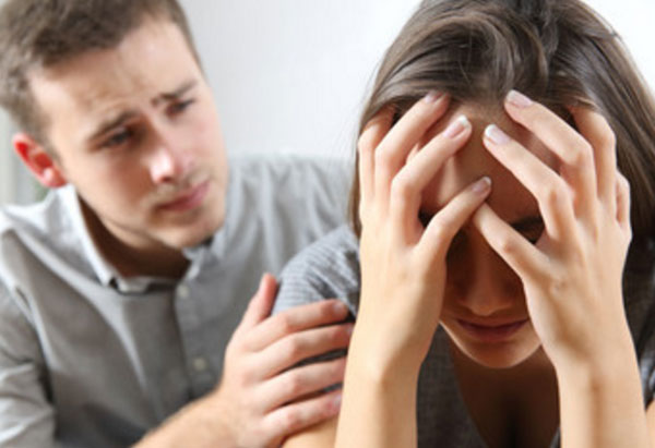 Девушка сидит в расстроенных чувствах, парень пытается ее поддержать