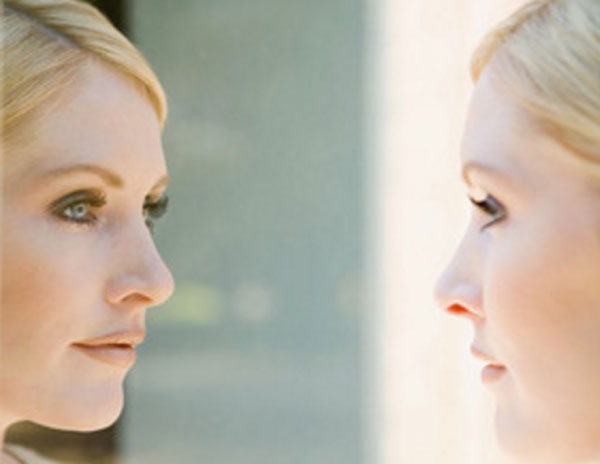 Женщина смотрит на себя в зеркало, умиротворенное лицо