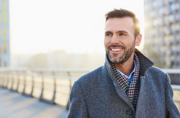 Улыбающийся мужчина прогуливается на улице