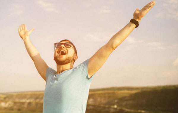 Счастливый мужчина в очках кричит от счастья. стоя на возвышенности