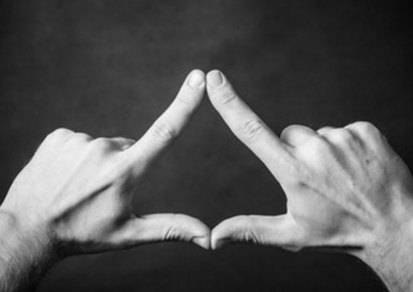 Человек при помощи рук формируют фигуру треугольника