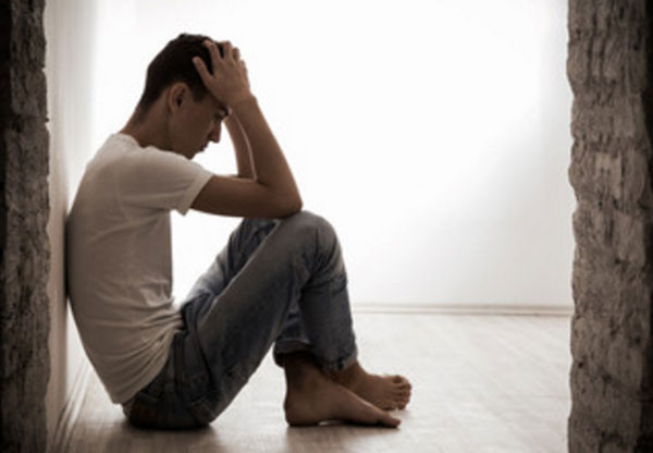 Парень сидит на полу. У него депрессия