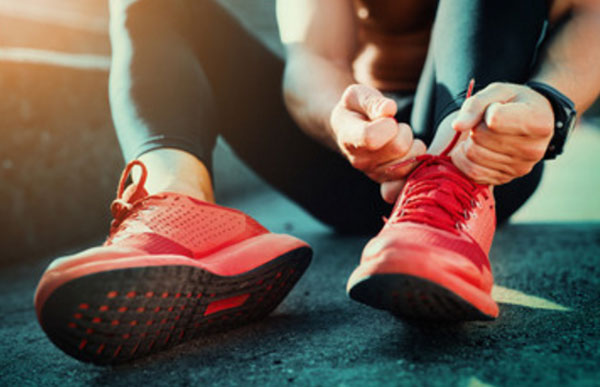 Мужчина завязывает шнурки на спортивной обуви