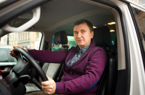 Веселый мужчина сидит за рулем машины