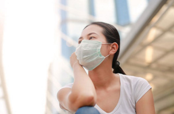 Женщина сидит на улице с маской на лице