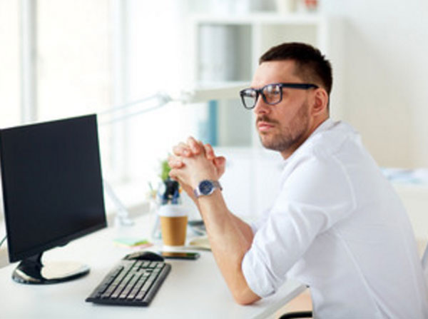 Парень сидит перед выключенным компьютером. Он задумался