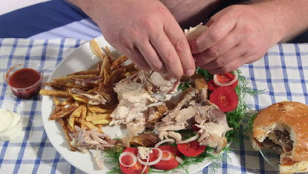 Большая тарелка с вредной едой и надкусанный бургер на столе