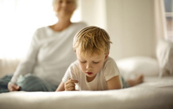 На переднем плане мальчик, который лежит на диване, на заднем - женщина