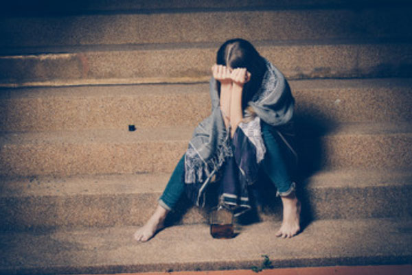 Девушка сидит на ступеньках. Она прячет свое лицо
