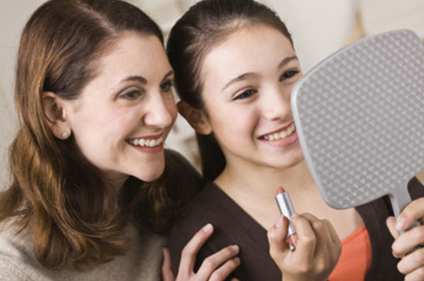 Мама с дочерью смотрятся в зеркало. У девочки в руке губная помада