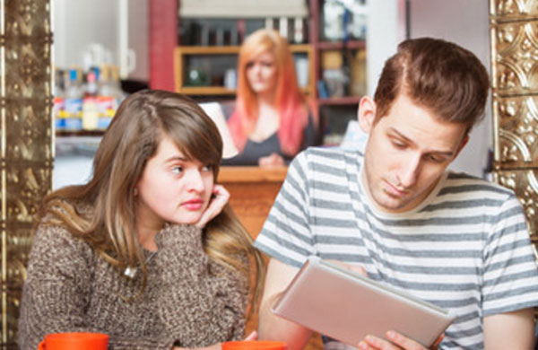 Парень что-то рассматривает в планшете, девушка укоризненно смотрит на него