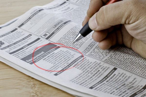 Человек обвел красной ручкой объявление с вакансией в газете