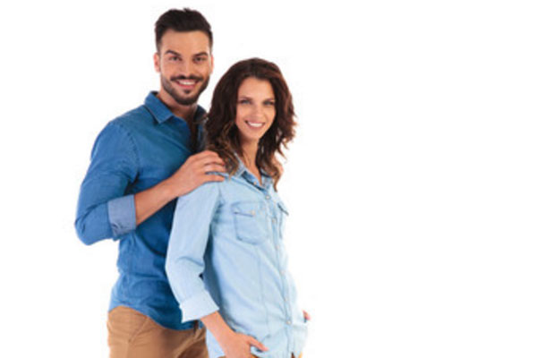 Мужчина стоит сзади женщины, обнимает ее за плечи