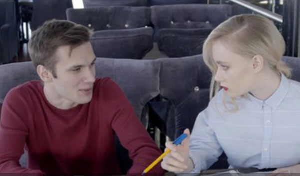 Мужчина и женщина сидят за столом. Женщина держит ручку