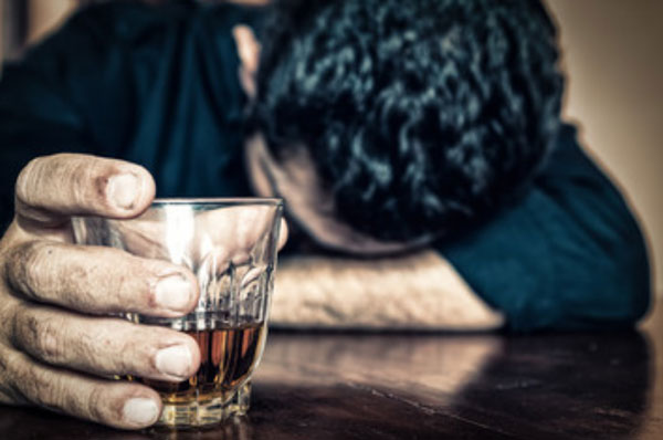 Мужчина с рюмкой в руке положил голову на стол