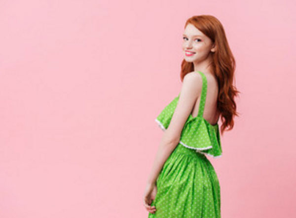 Улыбающаяся девушка в зеленом платье в белый горошек