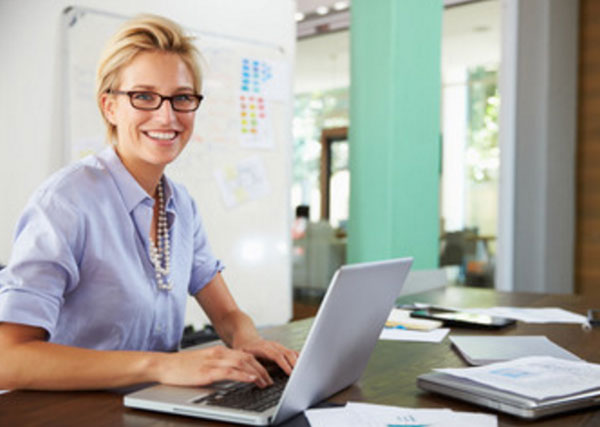 Улыбчивая женщина сидит за ноутбуком